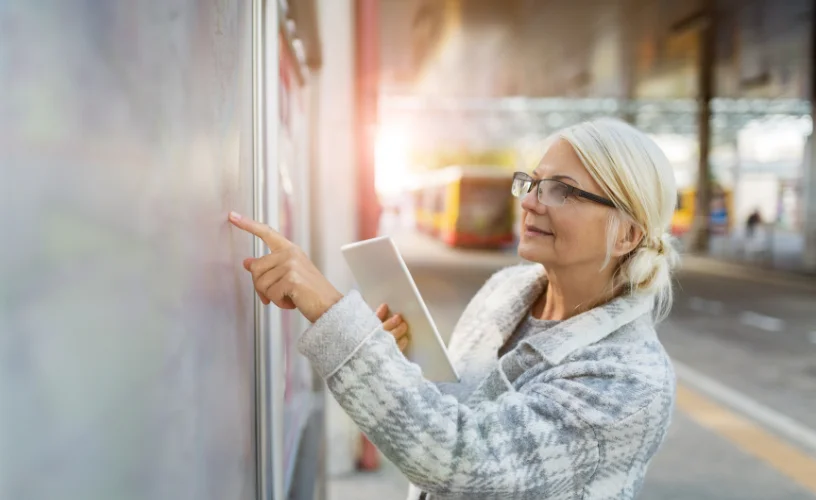 women looking at bus stop timetable display